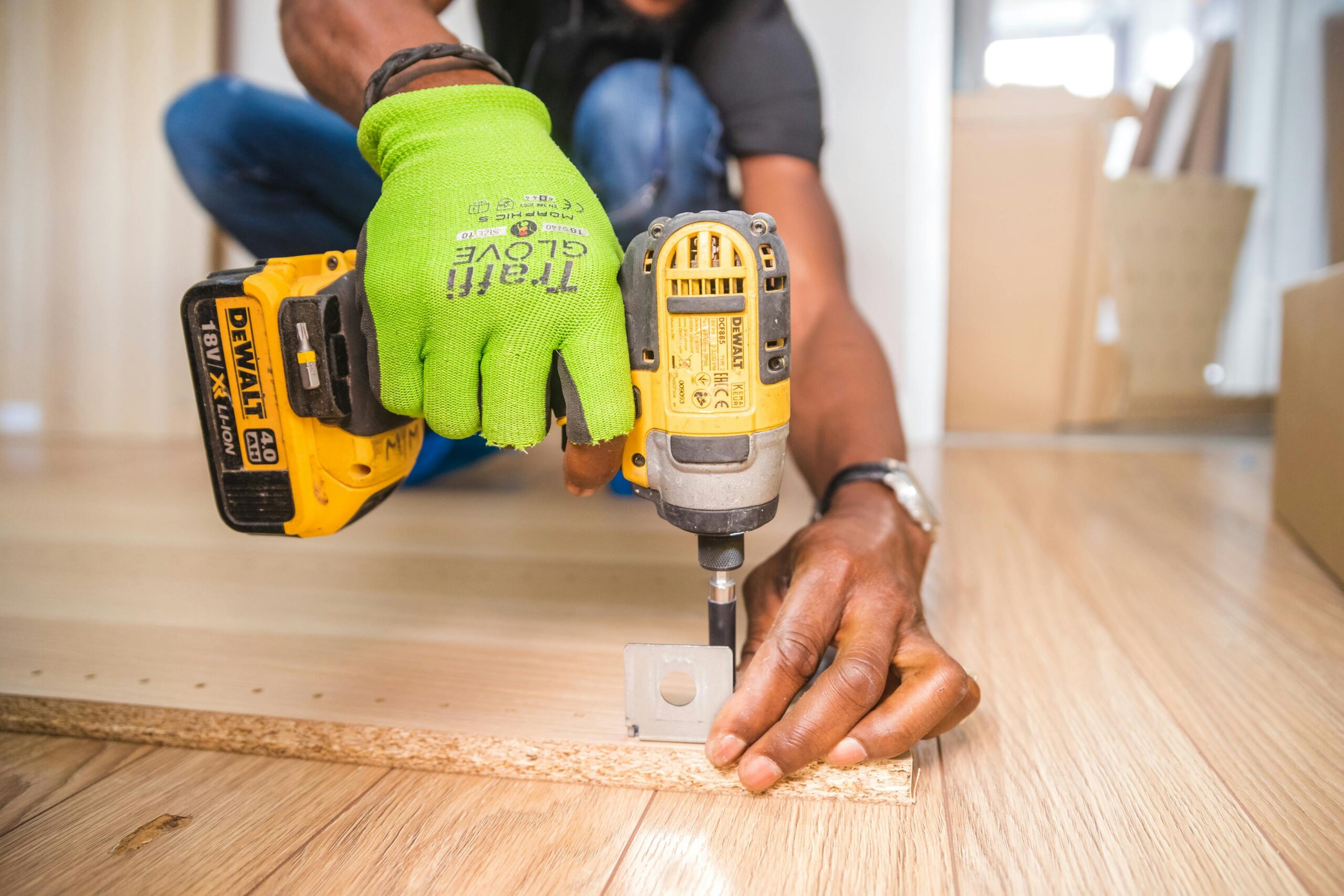 Man using a power drill for home improvement on a wooden floor with precision.