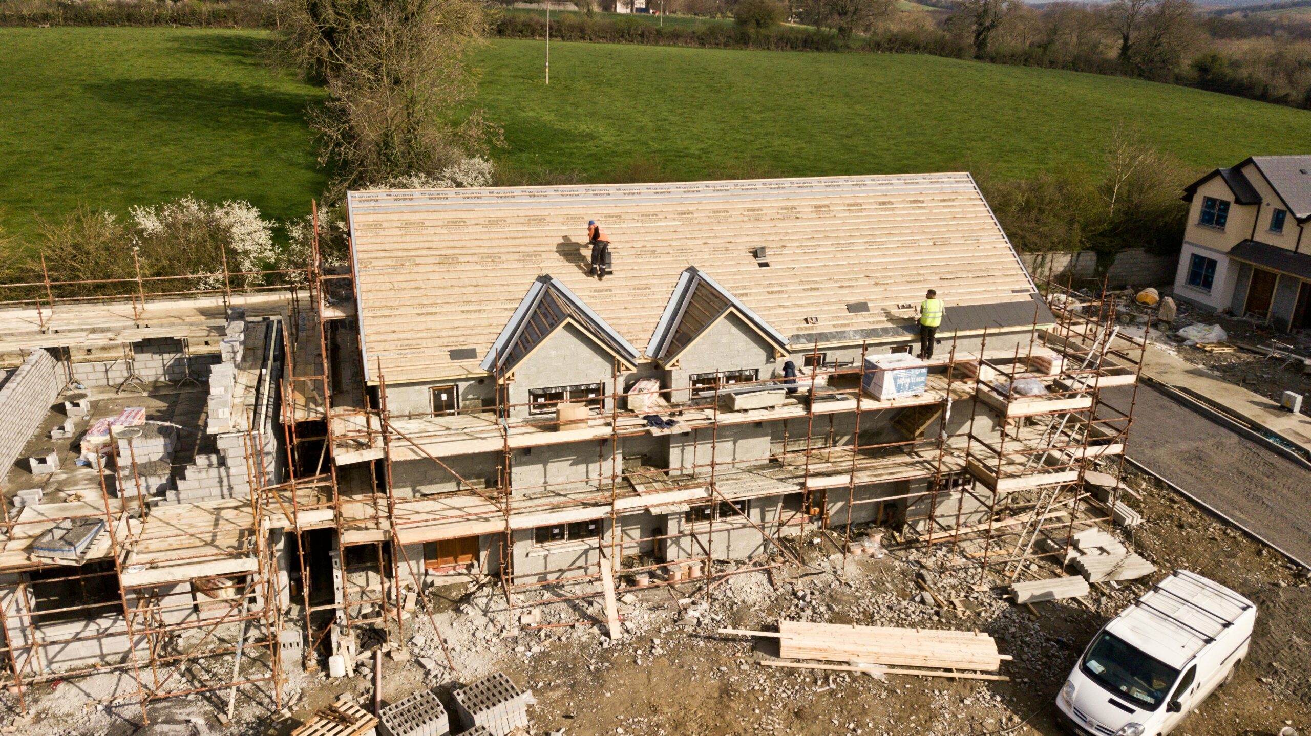 Aerial shot of a house under construction in Clonmel, Ireland. Workers on the roof.